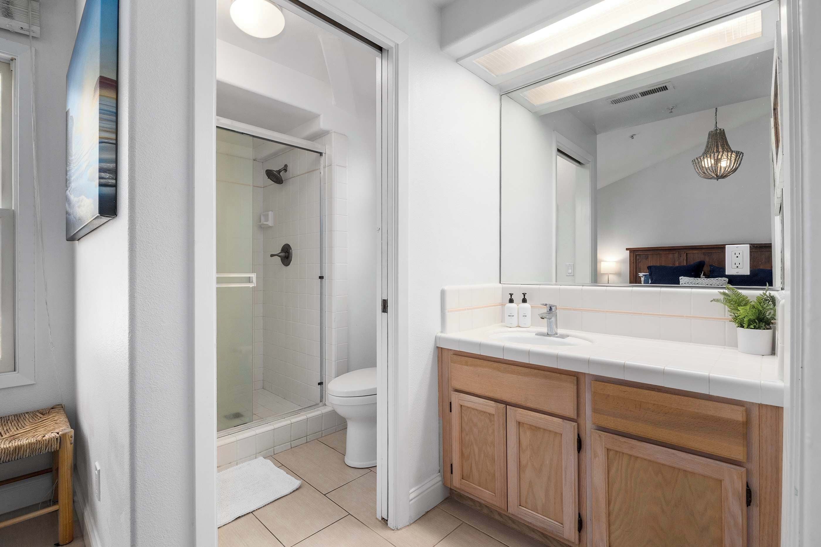 A modern bathroom with a glass shower enclosure, a white toilet, and a vanity with a mirror.