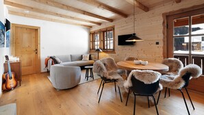 A wooden interior with a sofa, chairs, a dining table, and a guitar. - Holiday Appartment "Steinbock" in Sankt Anton am Arlberg with Mountain View, Balcony and Wi-Fi (Sankt Anton am Arlberg)