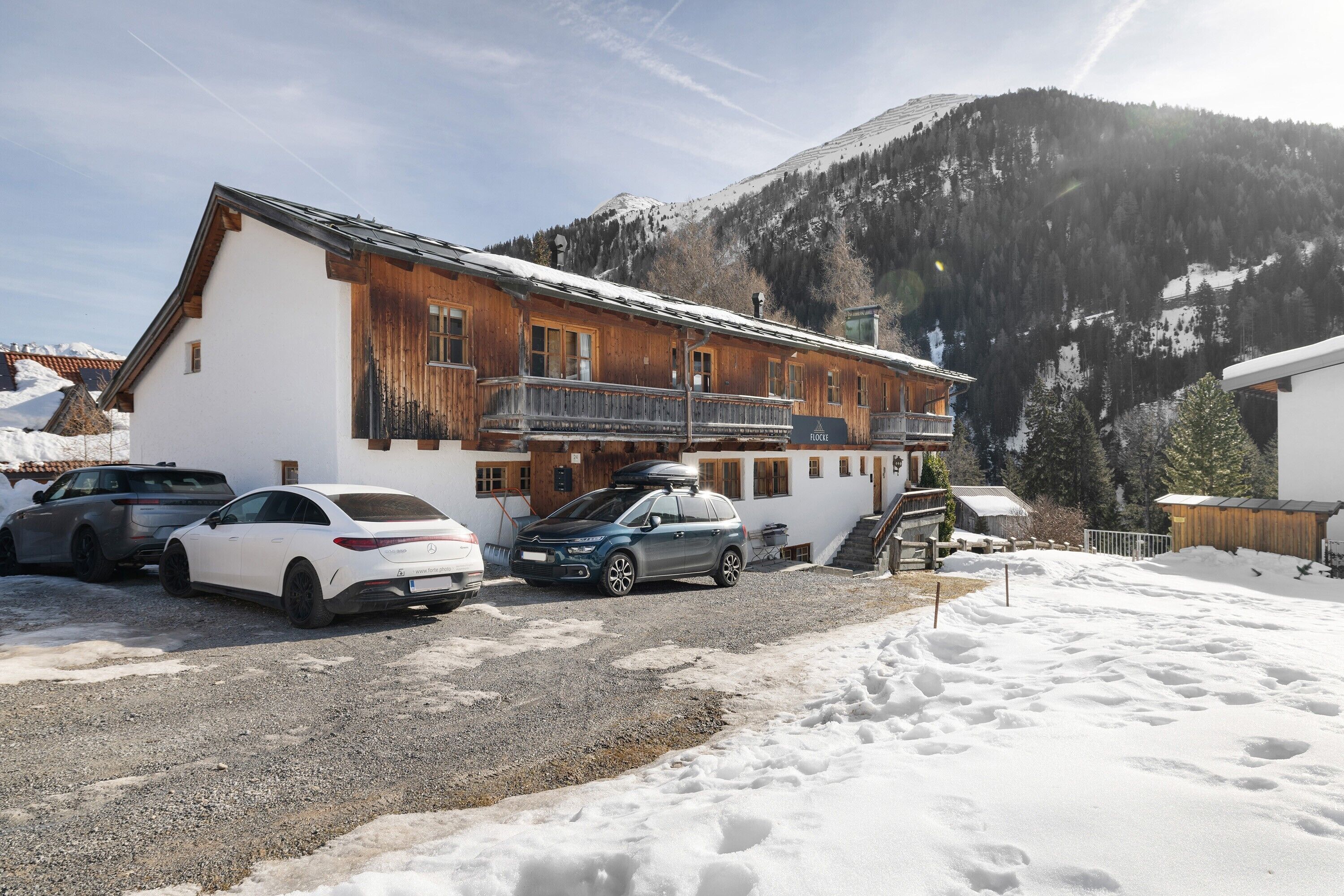 Un bâtiment avec une façade en bois, un balcon et une voiture garée devant.