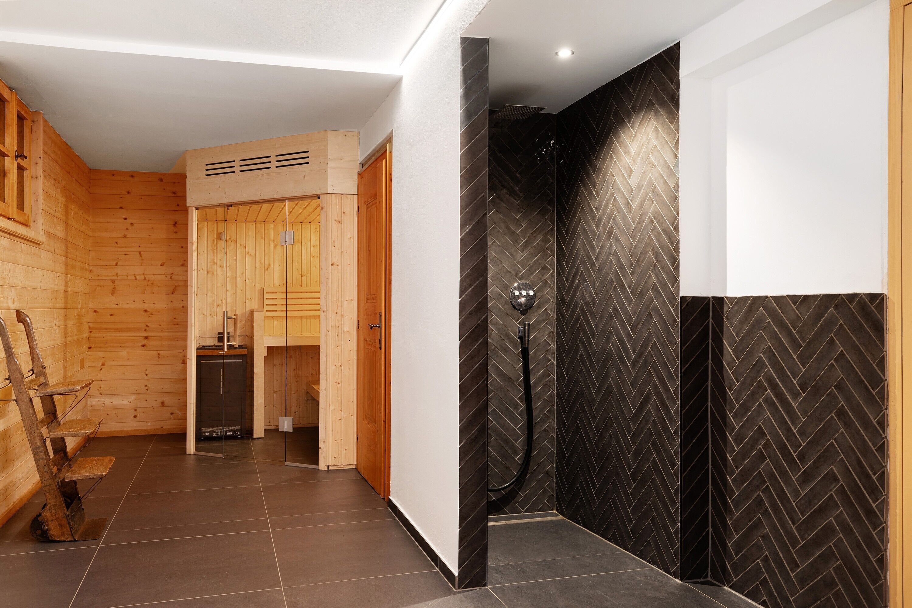Une salle de bain moderne avec une douche, des murs en bois et un mur recouvert de carreaux disposés en motif chevrons.