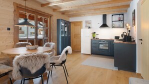 A modern kitchen with wooden beams, a dining area with a round table and chairs, and a refrigerator. - Holiday Appartment "Steinbock" in Sankt Anton am Arlberg with Mountain View, Balcony and Wi-Fi (Sankt Anton am Arlberg)