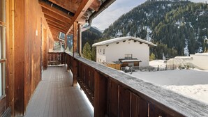 A wooden balcony with a view of a mountain and a building. - Holiday Appartment "Steinbock" in Sankt Anton am Arlberg with Mountain View, Balcony and Wi-Fi (Sankt Anton am Arlberg)