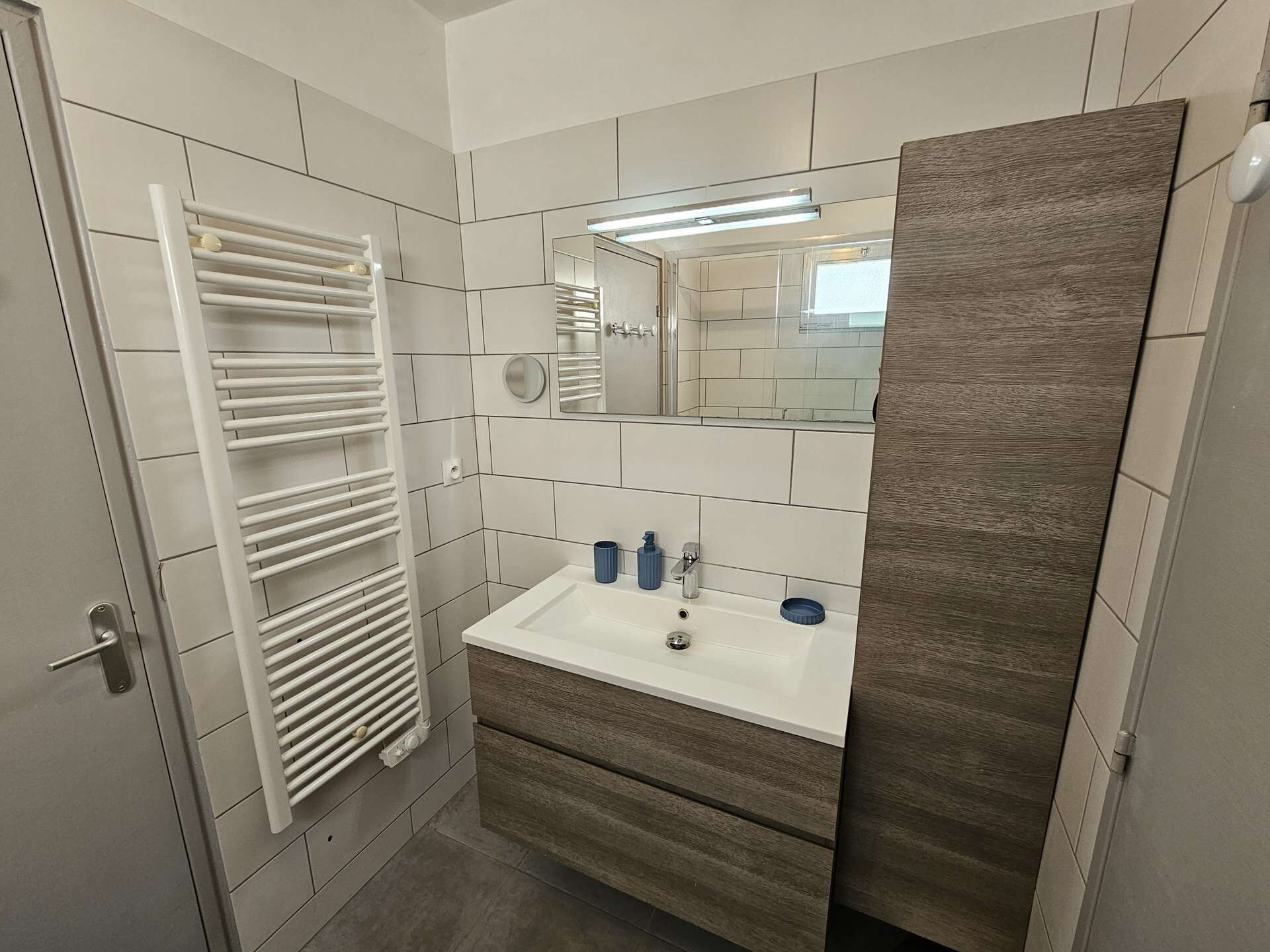 A bathroom with a white sink, mirror, and towel rack.