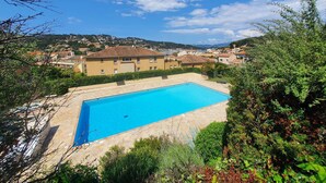 A swimming pool surrounded by greenery, with a building in the background and a clear sky. - Nice 1 bedroom apartment, WIFI, sea view, all on foot (ST MANDRIER SUR MER)