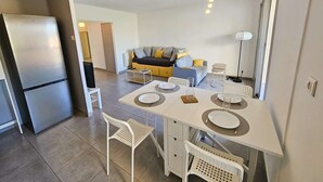 A modern kitchen with a dining area, a refrigerator, and a sofa in the background. - Nice 1 bedroom apartment, WIFI, sea view, all on foot (ST MANDRIER SUR MER)