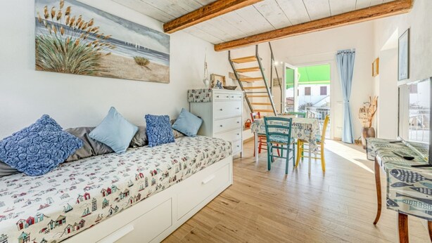 A cozy bedroom with a bed, dresser, and a staircase leading to a balcony.