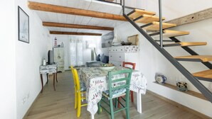 A dining area with a table set for two, a staircase, and a view of the upper floor.