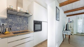 A modern kitchen with a patterned backsplash, a built-in oven, and wooden flooring.
