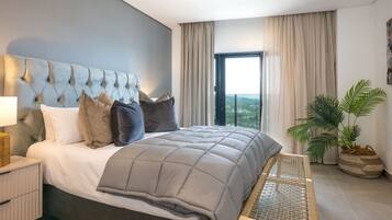 A modern bedroom with a large bed, a headboard with a unique design, a bedside table, a bench, and a view of the outdoors through a window.