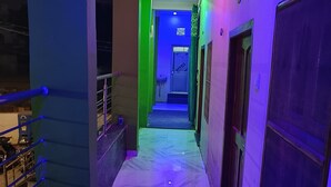 Un couloir doté d’un sol en marbre et, au bout, une porte illuminée d’une lumière verte.
