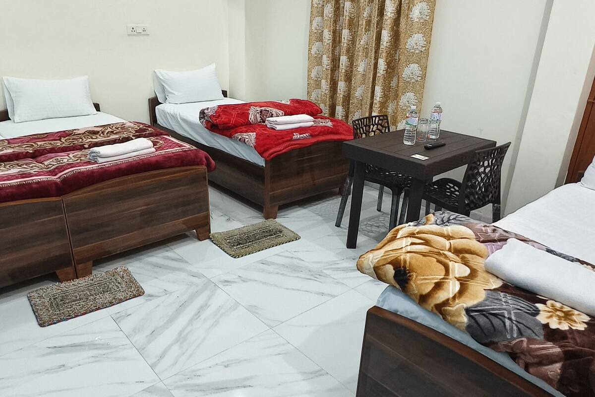 Habitación de hotel con dos camas, una mesita y sillas, y una puerta.