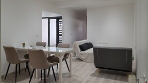 A modern living room with a glass dining table, four chairs, a sofa, and a dark cabinet. - ROOM 1 - ROOM in apartment, 2 min. walk from ferry dock (Papeete)