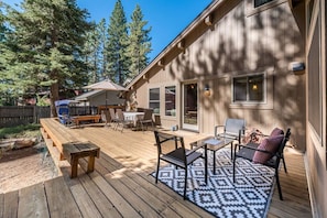 A wooden deck with outdoor furniture, including a table and chairs, and a patterned rug. - Majestic Pines Tahoe City (Tahoe City)