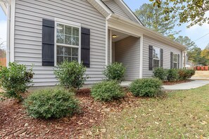 Welcome to this charming home with a cozy front porch and covered entryway, surrounded by a lush lawn and a beautiful tree.