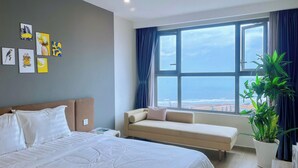 Ein Hotelzimmer mit Bett, einer Sitzecke, einem großen Fenster mit Meerblick und mehreren Wandbildern.