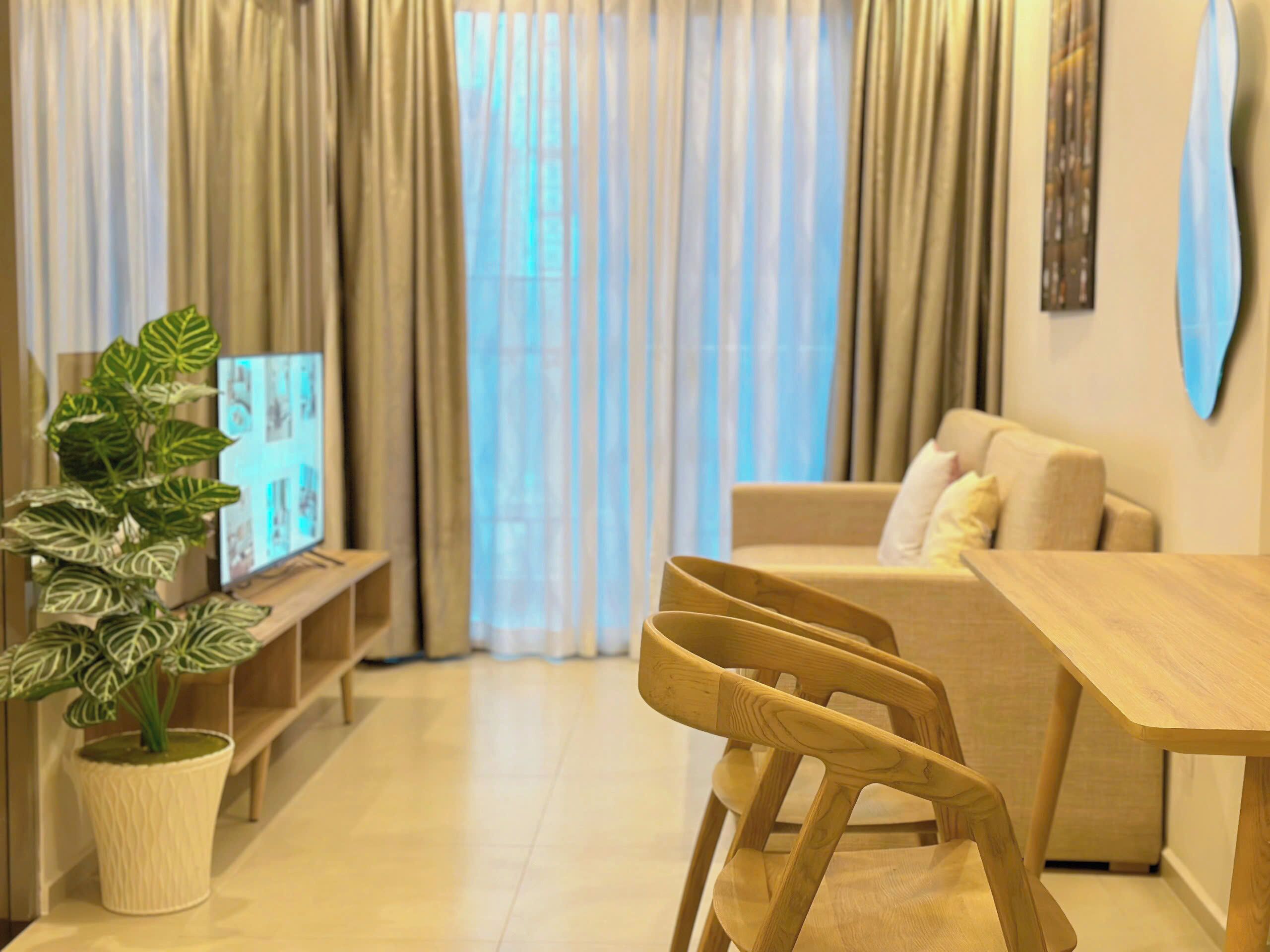 A living room with a sofa, a wooden dining table, and a plant.
