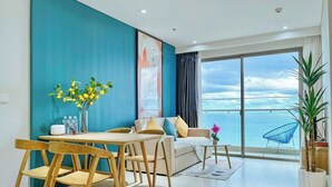 Ein modernes Wohnzimmer mit Essbereich, einer Couch und einem großen Fenster mit Meerblick.