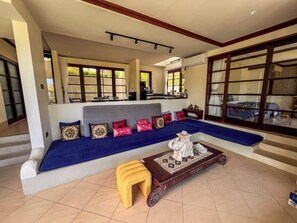 Una sala de estar con un sofá, una mesa de centro y vistas al exterior a través de amplios ventanales.