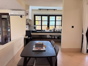 Una cucina moderna con zona pranzo, una finestra con persiane e vista su alberi.