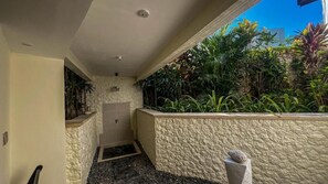 Un pasillo estrecho con una pared de piedra en un lado y un jardinero con diversas plantas en el otro.