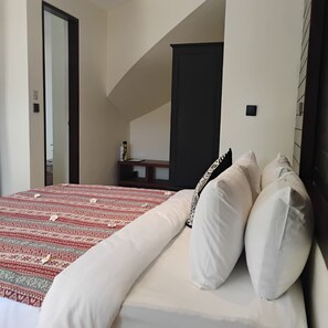 Une chambre d’hôtel comprenant un lit, une table de chevet, une armoire et une porte donnant sur une autre pièce.