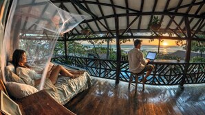 A couple relaxing on a wooden deck with a view of the sunset over the ocean.