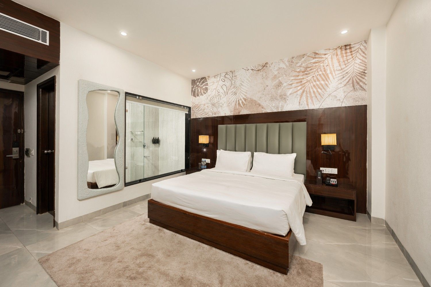 A modern bedroom with a large bed, a glass-enclosed shower, and a decorative wall mural.