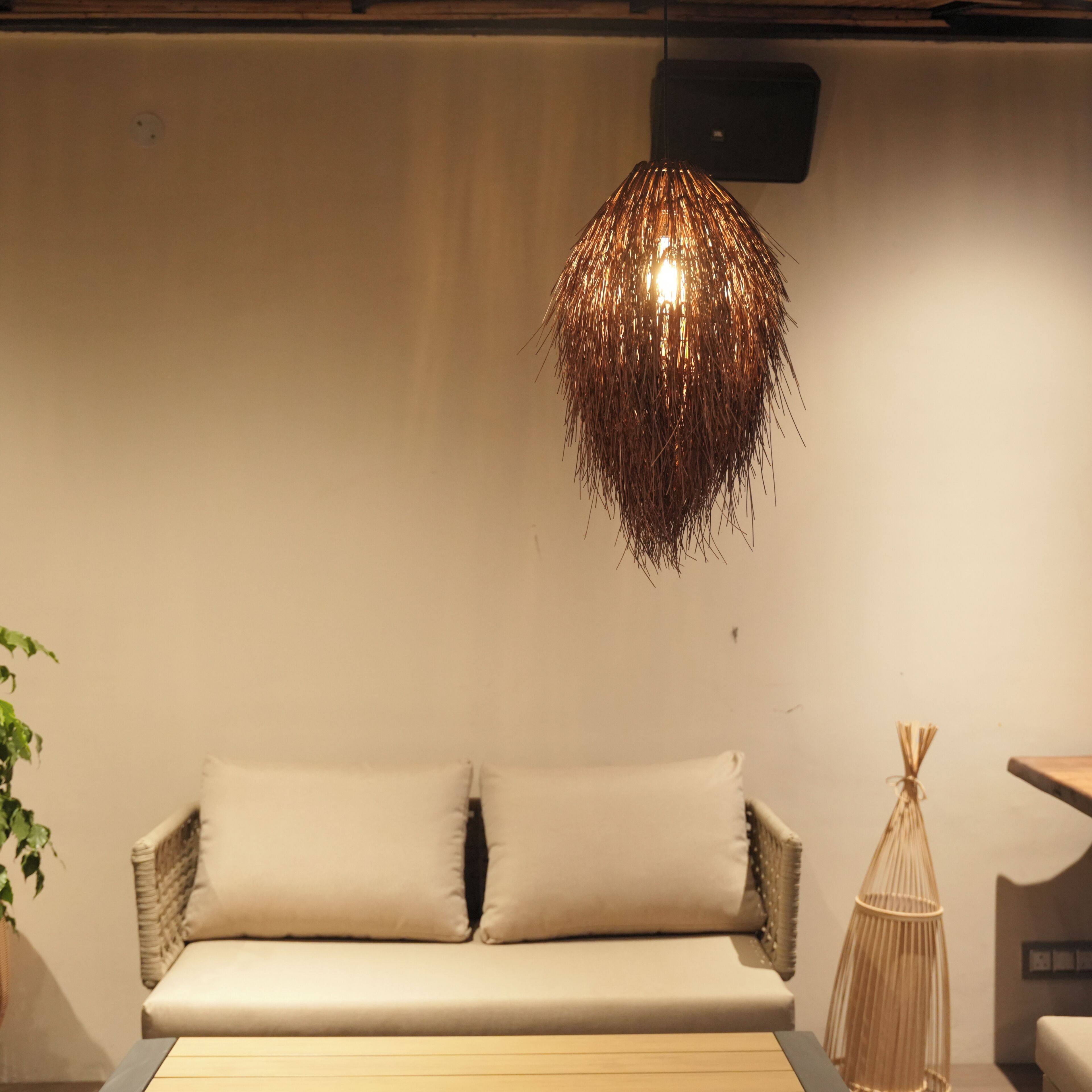 A modern living room with a wicker sofa, a wooden coffee table, and a hanging light fixture.