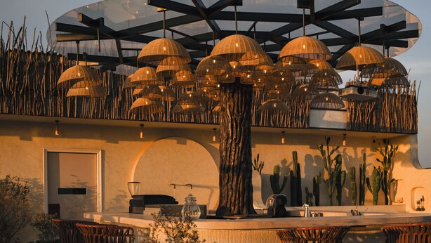An outdoor bar area with a modern design, featuring a large transparent umbrella structure, seating arrangements, and a central tree. - AVA Hotel Chandigarh Zirakpur (Dera Bassi)