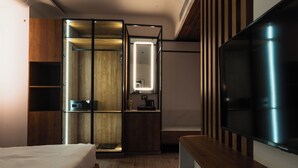 A modern hotel room with a bed, a wooden wardrobe, a built-in TV, and a small kitchenette. - AVA Hotel Chandigarh Zirakpur (Dera Bassi)