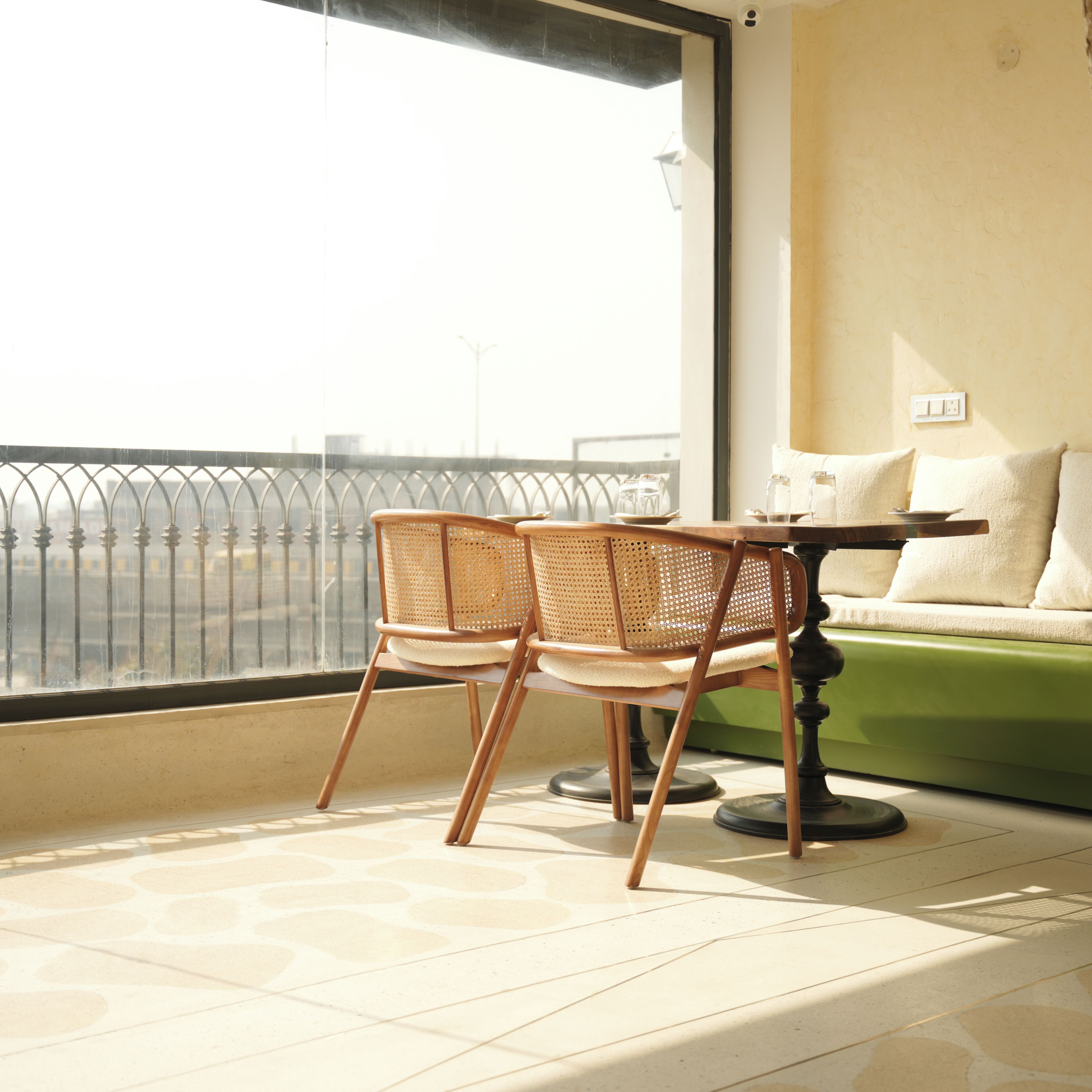 A balcony with two wicker chairs, a small table, and a sofa.