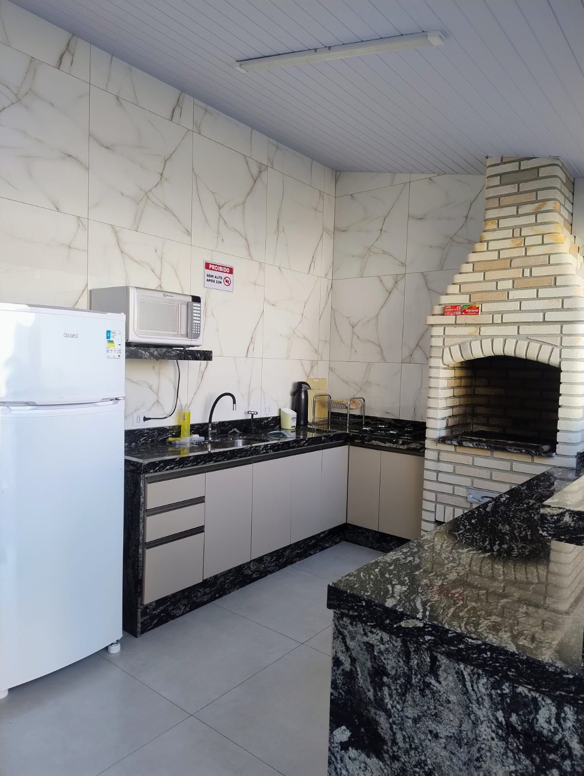 A kitchen with a built-in oven, a microwave, and a refrigerator.