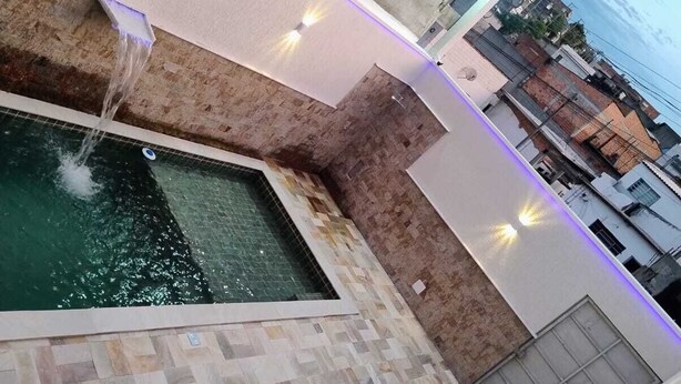 Una piscina en la azotea con fuente de agua y suelo de baldosas.