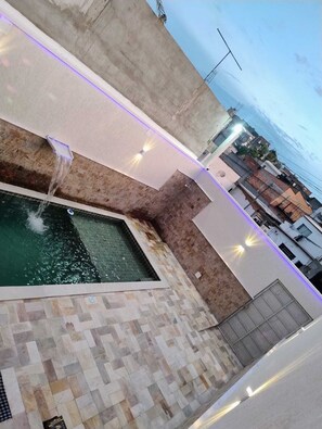 A rooftop pool with a water feature and a tiled floor.