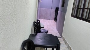 A narrow hallway with a table and chairs, a window with bars, and a security camera. - House with heated pool in Suzano - Leisure Space (Jardim São Bernadino Suzano)