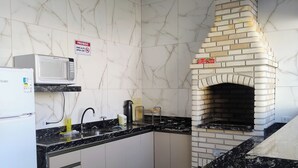 Una cocina con horno de ladrillo integrado, salpicadero de mármol blanco y encimeras negras.