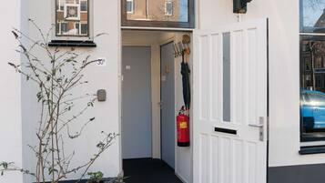 A building entrance with a white door, a small window, and a fire extinguisher mounted on the wall.