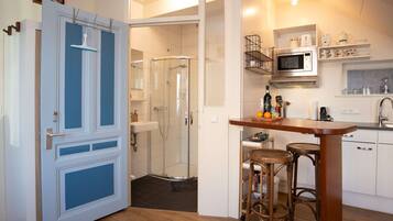 Een moderne keuken met een magnetron, spoelbak en barstoelen.
