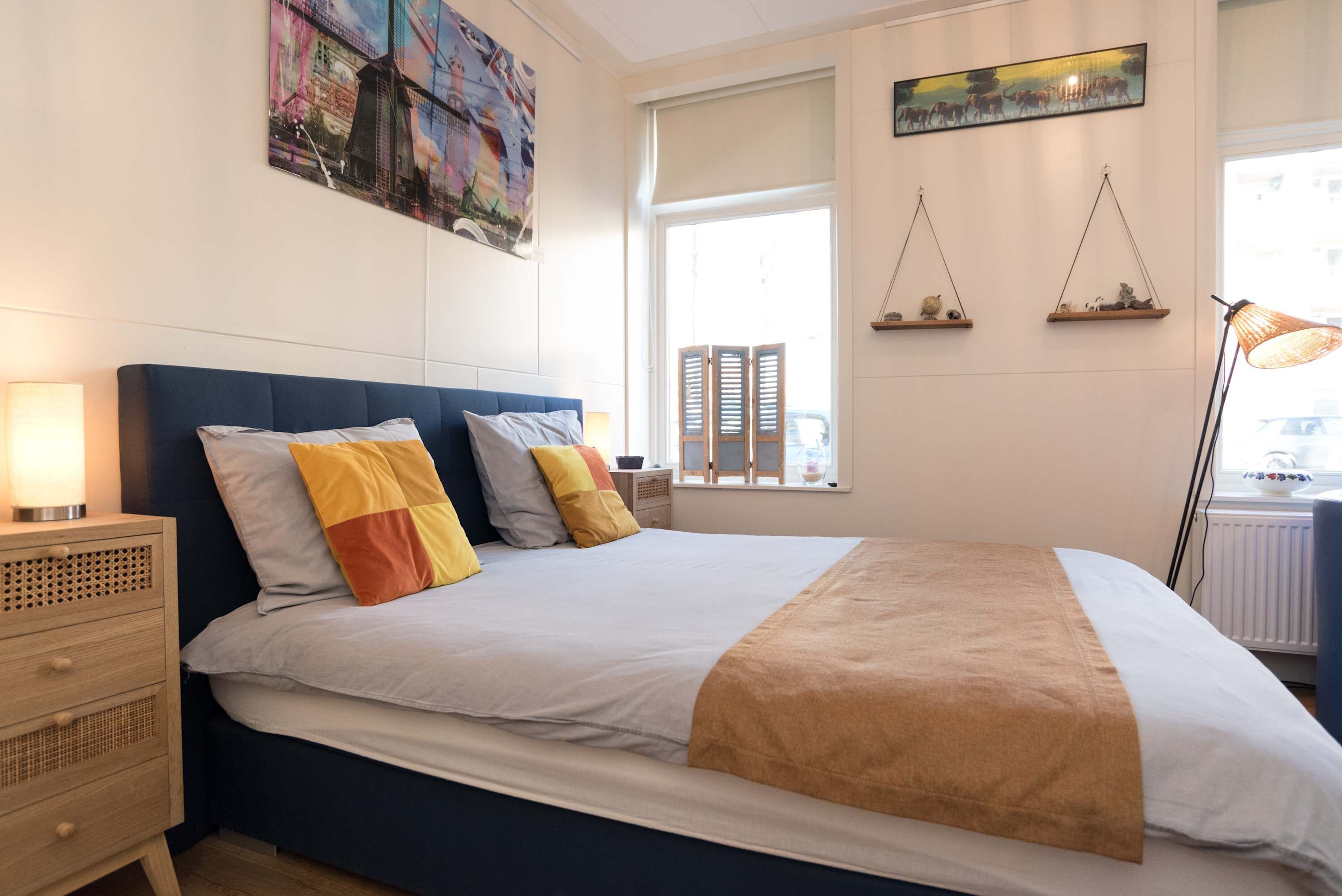 A neatly arranged bedroom with a bed, bedside tables, and wall art.