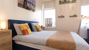 A neatly arranged bedroom with a bed, bedside tables, and wall art.