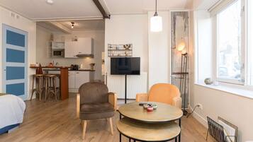 Un espace de vie compact comprenant une kitchenette, un coin repas et une chambre.
