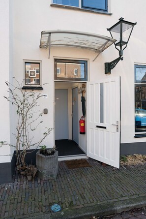 A building entrance with a white door, a small window, and a fire extinguisher mounted on the wall. - Luttik Oudorp 30B Apartment Alkmaar (Alkmaar)
