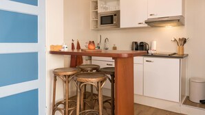 Uma cozinha compacta com uma ilha central, banquetas, micro-ondas e uma pia.