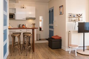 A compact kitchen with white cabinets, a microwave, and a small dining area with stools. - Luttik Oudorp 30B Apartment Alkmaar (Alkmaar)