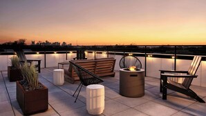 A rooftop terrace with seating, planters, and a fire feature. - Dreamy Condo with Fireplace, Rooftop, Gym, Parking  |  Sleeps 5 w/ King Bed, Sleeper Sofa, Hidden Bunk, Shared Rooftop and Gym, Free Dedicated Parking, Minutes to Broadway, Five Points & Grand Ole Opry, 24 Hr Hospitality (Nashville)