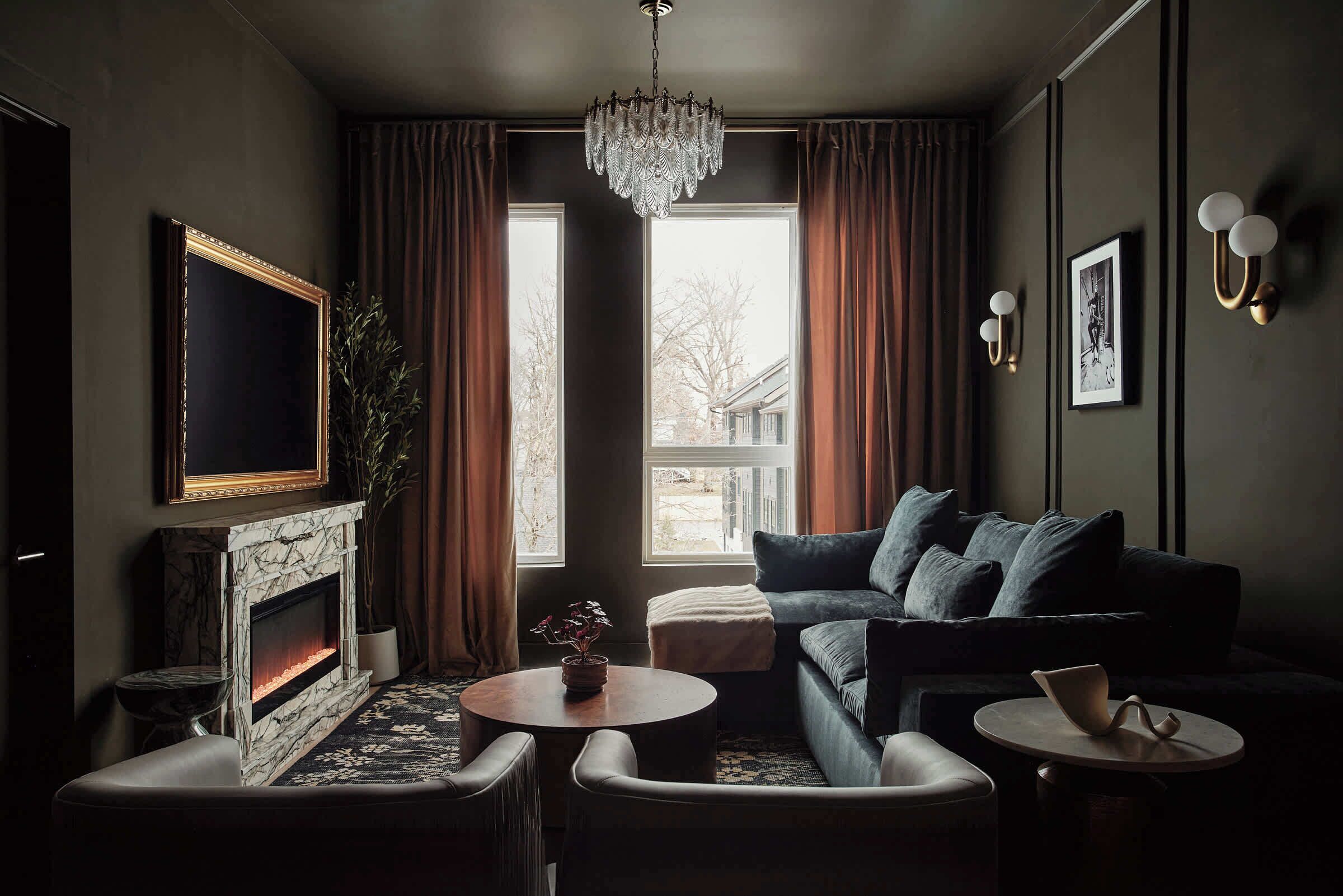 A modern living room with a fireplace, a sofa, a coffee table, and a chandelier.