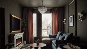 A modern living room with a fireplace, a sofa, a coffee table, and a chandelier. - Dreamy Condo with Fireplace, Rooftop, Gym, Parking  |  Sleeps 5 w/ King Bed, Sleeper Sofa, Hidden Bunk, Shared Rooftop and Gym, Free Dedicated Parking, Minutes to Broadway, Five Points & Grand Ole Opry, 24 Hr Hospitality (Nashville)