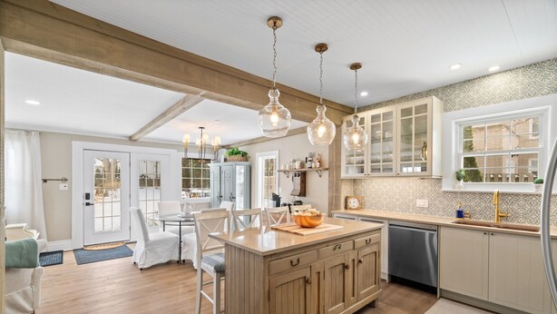 Una cocina moderna con armarios de madera, una isla central, iluminación colgante y vistas al comedor.