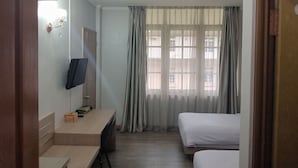 A hotel room with a bed, a desk, a TV, and a window with curtains. - Graha Dinar Hotel by HIMA (Cisarua)