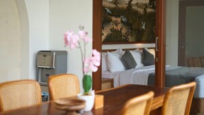Una camera d'albergo con un letto, una scrivania con un computer e un quadro raffigurante uccelli e alberi appeso al muro.
